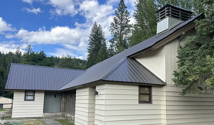 Cream lap siding and a new dark standing-seam metal roof on a Spokane property, showing the premium coatings and materials LAV Spokane Painting uses