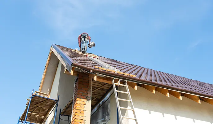 painter paints metal roof brown