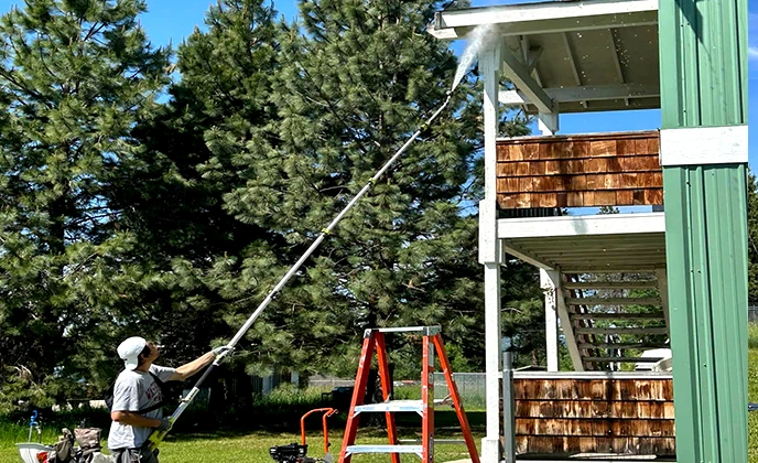 painter cleaning exterior of house with pressure washer