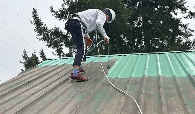 painter paints roof green after cleaning rust