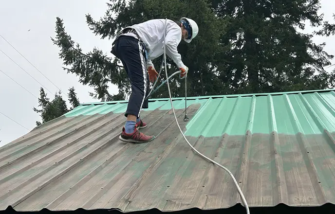 a painter applies the first coat of paint to a cleaned roof