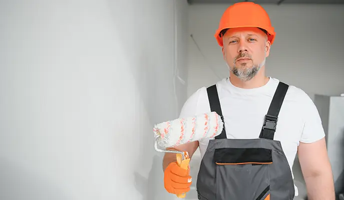 a painter with a pot and rollers in his hand is doing interior painting