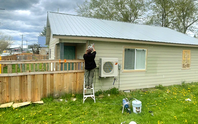 a painter is doing manual exterior painting of a house