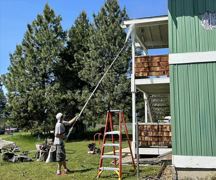 worker cleaning house with pressure washer