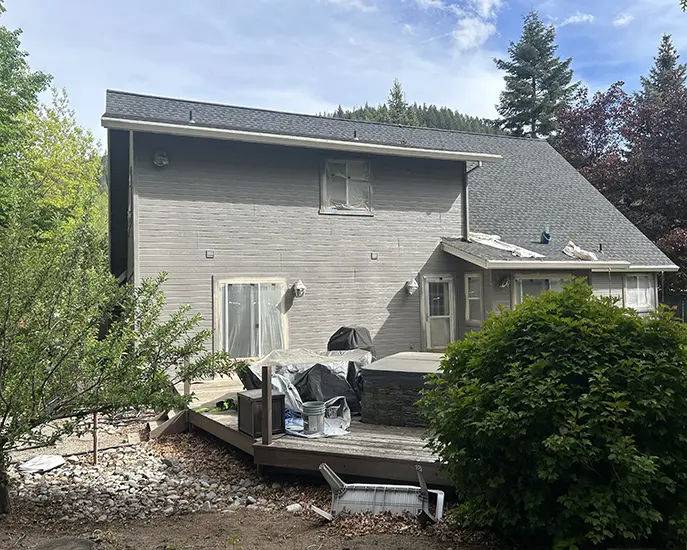 finished result of exterior painting of house in grey color and cleaned roof