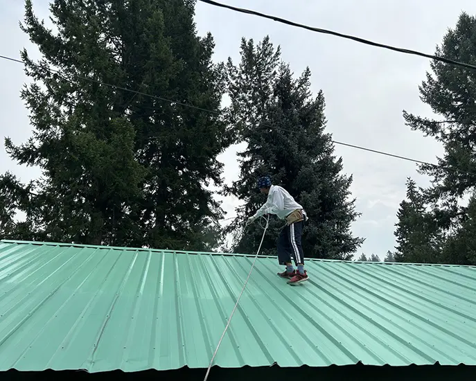 worker applies second coat of paint while painting roof