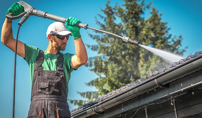 worker cleaning roof with pressure washer